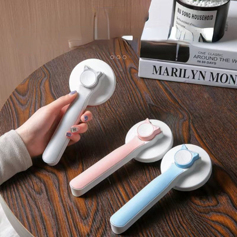 Three window cleaning squeegees in white, pink, and blue on a wooden surface with a hand holding one.