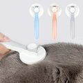 Pet grooming tool being used on a gray cat with three color options displayed above.